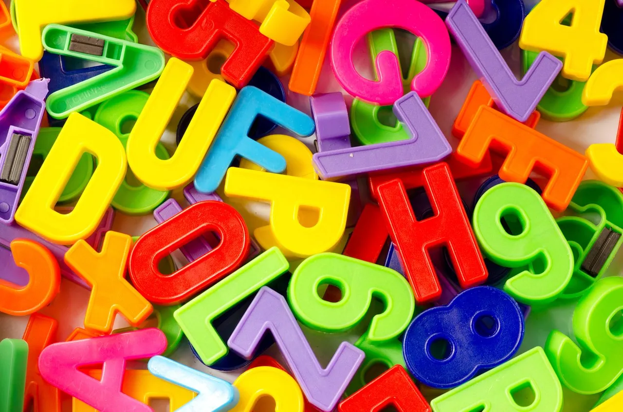 Image héros affichant des lettres de l'alphabet en plastique coloré (jaune, rouge, bleu, vert, rose, violet, orange) entrelacées sur un fond clair.